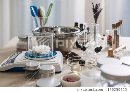 Glass beaker with solid oil sits on digital scale surrounded by laboratory equipment and ingredients. Custom oil blending, bespoke facial oils, personalized skincare routine, targeted beauty oils. Glass beaker with solid oil sits on digital scale surrounded by laboratory equipment and ingredients. Custom oil blending, bespoke facial oils, personalized skincare routine, targeted beauty oils. 136259523