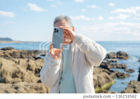 一名男子用智慧型手機拍攝海灘照片。 136259562