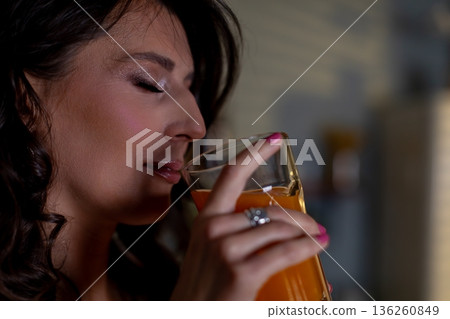 Quiet moment with orange fragrance, Peaceful woman relishes fragrant citrus aroma, Calm woman experiences mindfulness while inhaling sweet aroma of orange juice 136260849