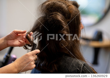Rear view stylist teasing hair volume, hands backlighting frizz and texture visible, fingers shaping sections, finishing product pending, focused salon prep mood Rear view stylist teasing hair volume, hands backlighting frizz and texture visible, fingers shaping sections, finishing product pending, focused salon prep mood 136260929