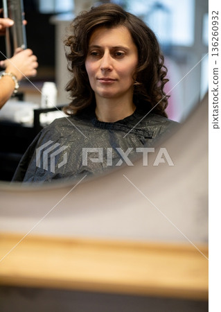 Stylish woman getting haircut, Relaxed woman seated as stylist carefully trims hair nearby, Casual scene of woman sitting calmly during professional hair cutting service Stylish woman getting haircut, Relaxed woman seated as stylist carefully trims hair nearby, Casual scene of woman sitting calmly during professional hair cutting service 136260932
