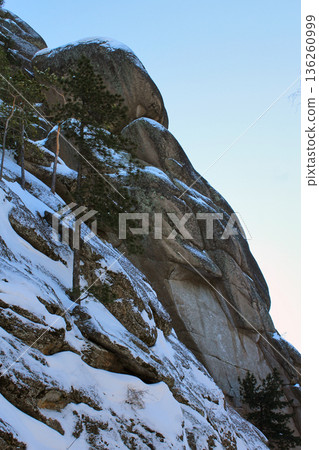Snow covered granite rock formation in Krasnoyarsk Pillars national park. Winter landscape for nature and travel content. Siberian nature concept. Snow covered granite rock formation in Krasnoyarsk Pillars national park. Winter landscape for nature and travel content. Siberian nature concept. 136260999