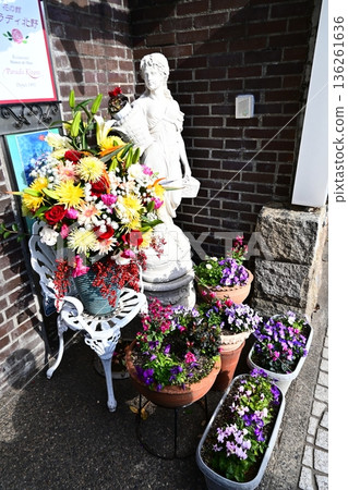 Stone statues and vibrant flowers decorate the entrance to the Western-style building 136261636