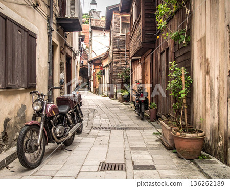 A retro scene with a vintage bike standing in a back alley lined with old wooden houses 136262189