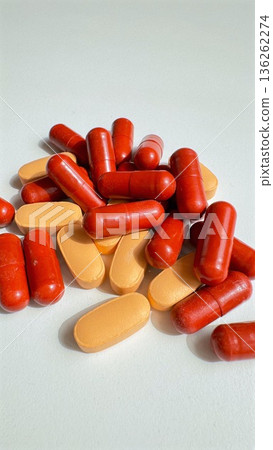 Colorful Capsules Stacked Vertically. Bright Capsules Arranged In Vertical Display. Dynamic Arrangement Of Red And Orange Capsules Emphasizing Energetic Brand Messaging Colorful Capsules Stacked Vertically. Bright Capsules Arranged In Vertical Display. Dynamic Arrangement Of Red And Orange Capsules Emphasizing Energetic Brand Messaging 136262274
