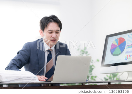 畫面中，一位身著西裝的男士，神情焦慮、心事重重、忙碌不堪、焦躁不安，他可能是位總裁或經理，正在查看一張業務戰略和業績圖表。 136263106
