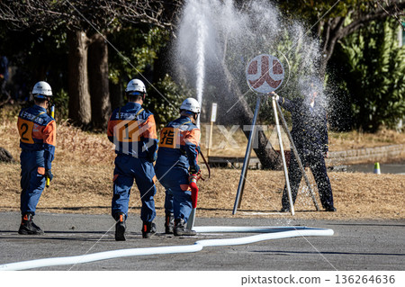 Firefighters demonstrating water spraying training at a target during the New Year's ceremony Firefighters demonstrating water spraying training at a target during the New Year's ceremony 136264636