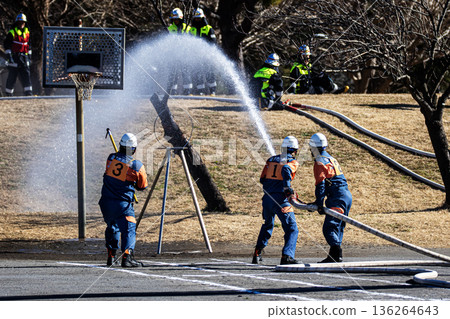Firefighters demonstrating water spraying training at a target during the New Year's ceremony Firefighters demonstrating water spraying training at a target during the New Year's ceremony 136264643