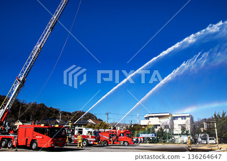 Firefighters demonstrate simultaneous water spraying training into the blue sky at the New Year's ceremony Firefighters demonstrate simultaneous water spraying training into the blue sky at the New Year's ceremony 136264647