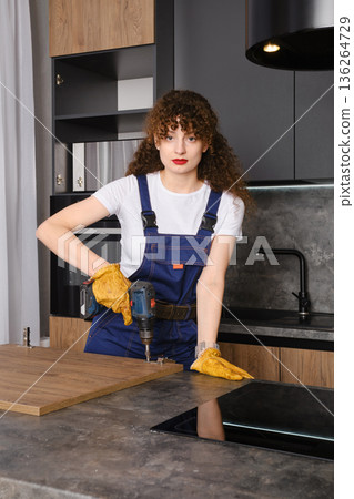 A young woman assembles the facade of kitchen furniture using a screwdriver A young woman assembles the facade of kitchen furniture using a screwdriver 136264729