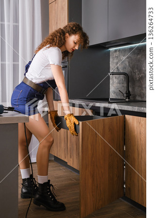 Woman installing pull-out shelf in kitchen cabinet Woman installing pull-out shelf in kitchen cabinet 136264733