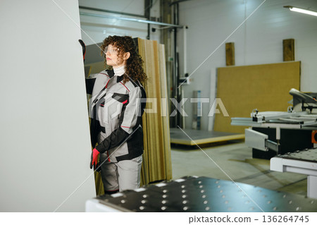 Worker cuts a large sheet in a workshop in broad daylight Worker cuts a large sheet in a workshop in broad daylight 136264745