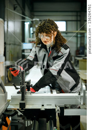 Worker operates a machine in a factory setting during daytime Worker operates a machine in a factory setting during daytime 136264761