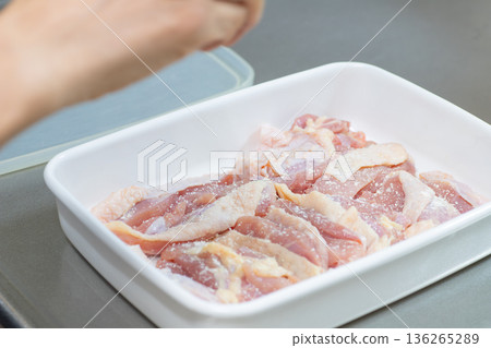 一隻女人的手正在往雞腿上撒調味料 136265289
