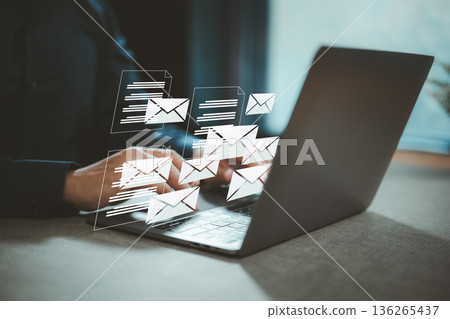 Typing on laptop with digital email and message icons representing communication and online correspondence 136265437