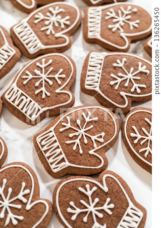 Close-up of beautifully decorated mitten-shaped gingerbread cookies featuring intricate white royal icing designs, arranged on a marble surface. Close-up of beautifully decorated mitten-shaped gingerbread cookies featuring intricate white royal icing designs, arranged on a marble surface. 136265450