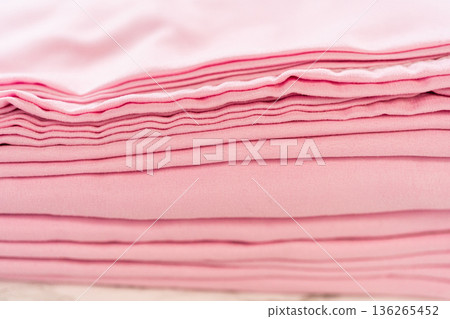 A horizontal arrangement of soft pink folded fabric layers captured from a low angle. The smooth creases and light pastel tones create a visually soothing pattern. A horizontal arrangement of soft pink folded fabric layers captured from a low angle. The smooth creases and light pastel tones create a visually soothing pattern. 136265452