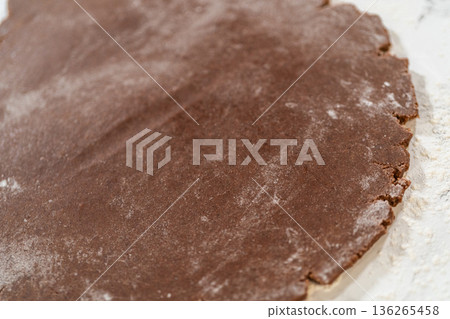 Overhead view of flattened dough for Pale Gingerbread Cookies on a floured marble surface, prepared for cutting out mitten shapes. Overhead view of flattened dough for Pale Gingerbread Cookies on a floured marble surface, prepared for cutting out mitten shapes. 136265458