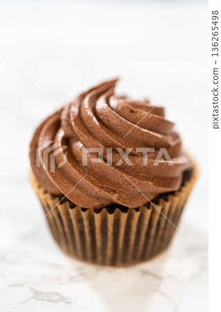 A single, indulgent chocolate cupcake sits gracefully on the kitchen counter, tempting your taste buds. A single, indulgent chocolate cupcake sits gracefully on the kitchen counter, tempting your taste buds. 136265498