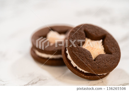 A close detail view shows chocolate sandwich cookies with star cutouts and piped frosting. Lighting highlights smooth filling texture. A close detail view shows chocolate sandwich cookies with star cutouts and piped frosting. Lighting highlights smooth filling texture. 136265506