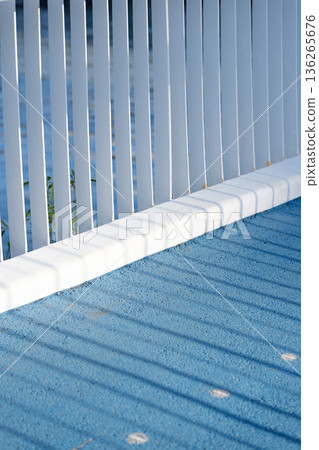 Minimalistic urban background with the shadow of a white fence falling on a blue floor Minimalistic urban background with the shadow of a white fence falling on a blue floor 136265676