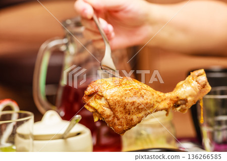 Human hand holding cooked chicken on fork 136266585