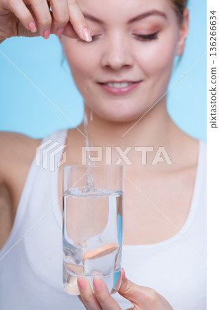 Woman holding glass with water and effervescent tablet Woman holding glass with water and effervescent tablet 136266634