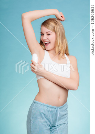 Girl applying stick deodorant in armpit. 136266635