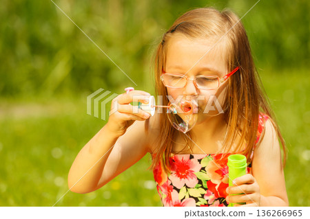 Little girl having fun blowing soap bubbles in park. Little girl having fun blowing soap bubbles in park. 136266965