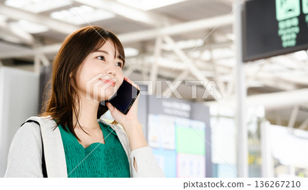 A woman talking on a cell phone at the airport. Photo courtesy of Kansai International Airport (KIX). 136267210