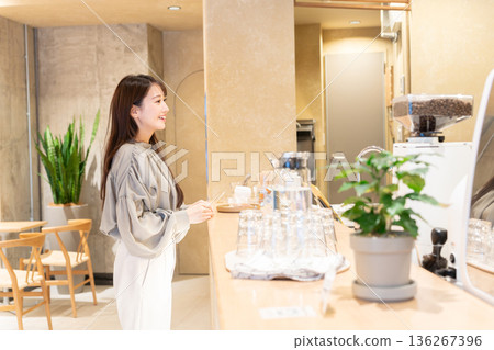 Young woman standing in front of the counter at a cafe Young woman standing in front of the counter at a cafe 136267396