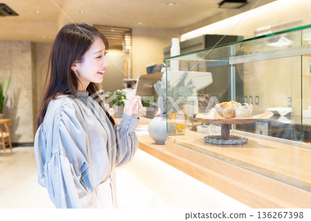 Young woman standing in front of the counter at a cafe Young woman standing in front of the counter at a cafe 136267398