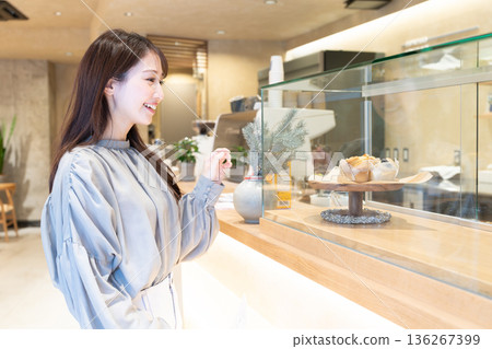 Young woman standing in front of the counter at a cafe Young woman standing in front of the counter at a cafe 136267399