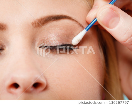 Woman getting her makeup done with cotton buds Woman getting her makeup done with cotton buds 136267797