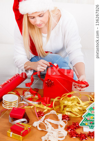 Woman in Santa hat preparing christmas gifts Woman in Santa hat preparing christmas gifts 136267826