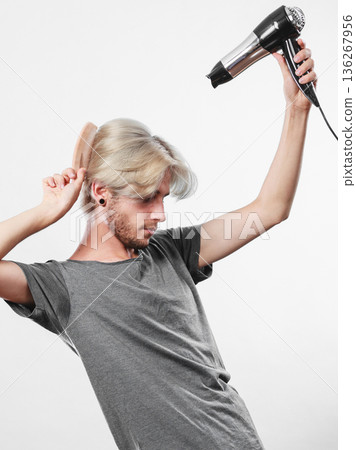Young man drying hair with hairdryer Young man drying hair with hairdryer 136267956
