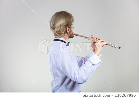 Male flutist playing his flute Male flutist playing his flute 136267980
