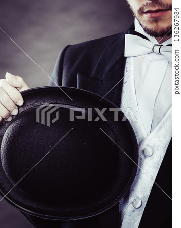 Elegantly dressed man holding black fedora hat Elegantly dressed man holding black fedora hat 136267984