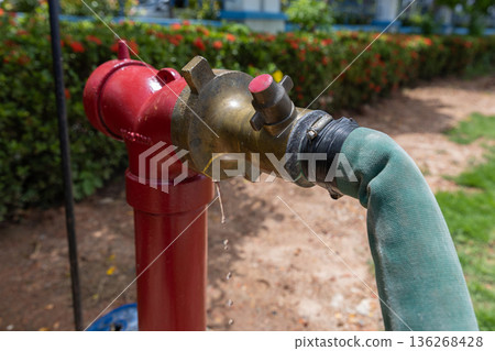 Red hydrant with hose plugs in case of emergency on a sidewalk. Red hydrant with hose plugs in case of emergency on a sidewalk. 136268428
