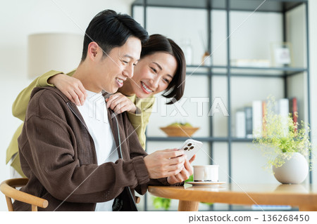 一對中年夫妻在家看智慧型手機 一對中年夫妻在家看智慧型手機 136268450