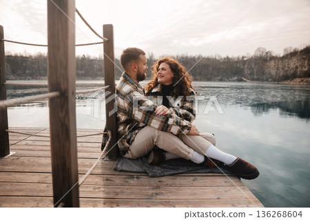 Couple sitting on a dock by the lake enjoying a day together near water during a romantic outing in winter 136268604