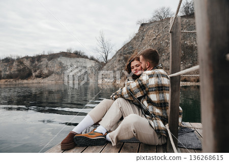 Couple enjoys a moment by the water on a cool day while celebrating love and sharing a peaceful time together Couple enjoys a moment by the water on a cool day while celebrating love and sharing a peaceful time together 136268615