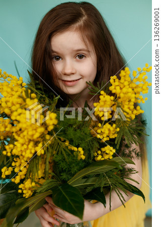 Girl with yellow mimosa bouquet on turquoise background Girl with yellow mimosa bouquet on turquoise background 136269001