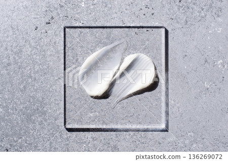 A sample of white body cosmetics on a glass square. Grey background. 136269072
