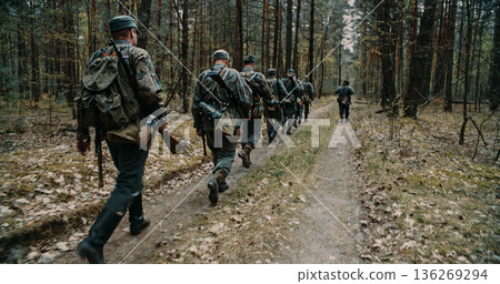German soldiers marching in forest formation during WWII reenactment 136269294