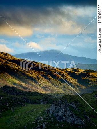 Hills and valleys meet the cloudy horizon. 136269351