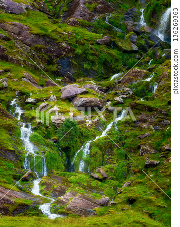 Lush green waterfall cascading over mossy rocks. Lush green waterfall cascading over mossy rocks. 136269363