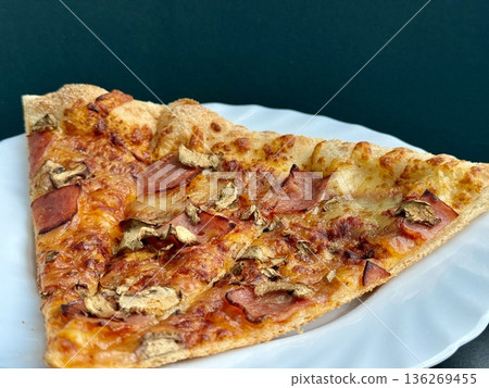 A close-up shot of a large classic pizza with cheese, ham, and mushrooms. A delicious, nutritious, and quick meal. 136269455