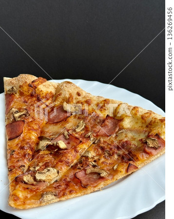 A close-up shot of a large classic pizza with cheese, ham, and mushrooms. A delicious, nutritious, and quick meal. A close-up shot of a large classic pizza with cheese, ham, and mushrooms. A delicious, nutritious, and quick meal. 136269456