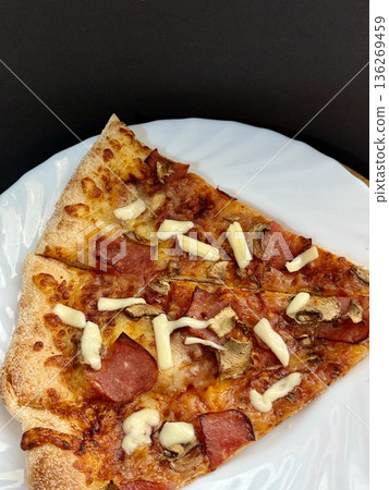 A close-up shot of a large classic pizza with cheese, ham, and mushrooms. A delicious, nutritious, and quick meal. A close-up shot of a large classic pizza with cheese, ham, and mushrooms. A delicious, nutritious, and quick meal. 136269459